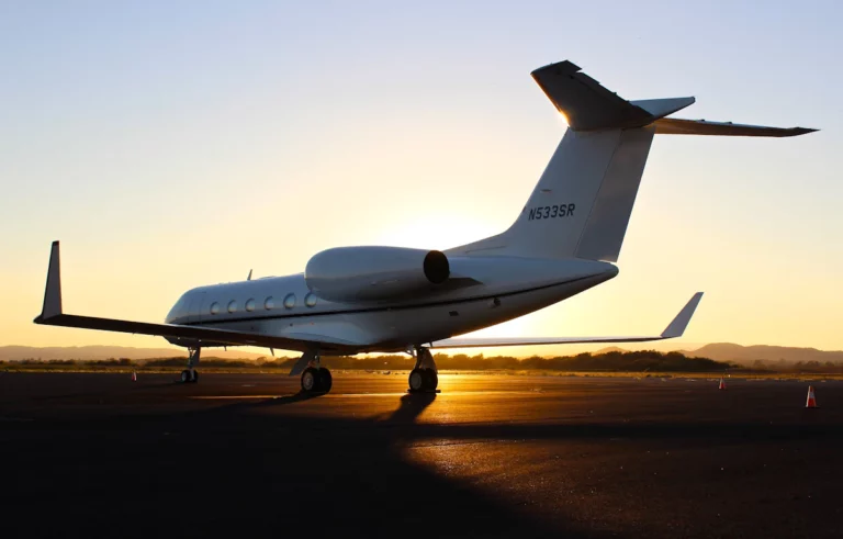 Un jet privé blanc sur un tarmac d’aéroport pendant l’heure dorée